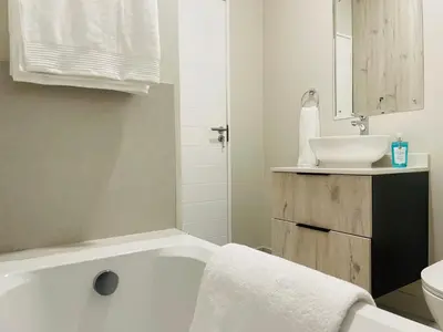 a bathroom with a white tub and a sink at Mikeys place On New: 2bed2bath no.1 with Free WiFiNetflix in Midrand