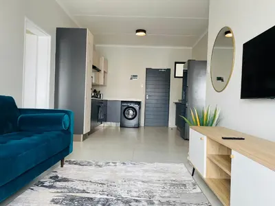a living room with a blue couch and a kitchen at Mikeys place On New: 2bed2bath no.1 with Free WiFiNetflix in Midrand