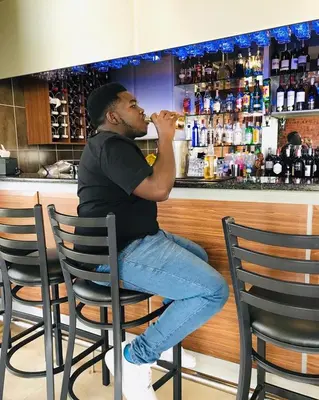 a man sitting in a bar drinking a drink at MGB Hotel at 2ten in Thohoyandou
