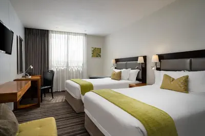 a hotel room with two beds and a desk at Premier Hotel Midrand in Midrand
