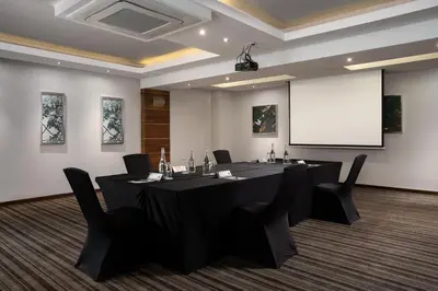 a conference room with a black table and chairs and a screen at Premier Hotel Midrand in Midrand