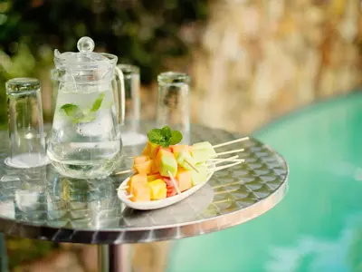 a plate of fruit on a glass table with a drink at Premier Hotel Midrand in Midrand