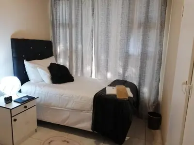 a bedroom with a bed and a window with curtains at Montana Guest House in Pretoria