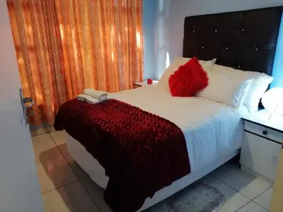 a bedroom with a bed with a red pillow on it at Montana Guest House in Pretoria
