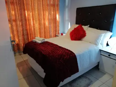 a bedroom with a bed with red pillows on it at Montana Guest House in Pretoria