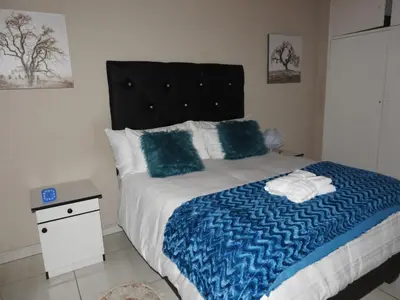 a bedroom with a bed with blue and white sheets at Montana Guest House in Pretoria