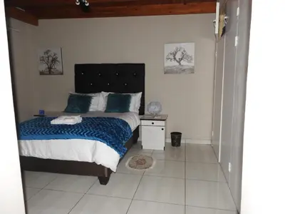 a bedroom with a bed with a blue blanket at Montana Guest House in Pretoria