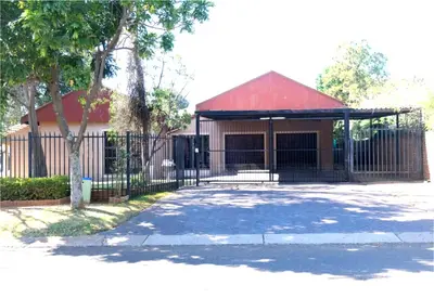 a gate in front of a building with a red roof at Montana Guest House in Pretoria