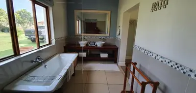 a bathroom with a tub and a sink and a mirror at Riverside Farm in Witbank