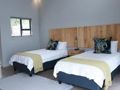 a bedroom with two beds with white sheets and a wooden headboard at Elements Bush Lodge in Moheme
