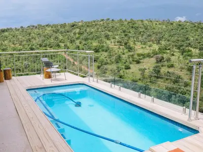 a swimming pool on a balcony with a mountain in the background at Elements Bush Lodge in Moheme