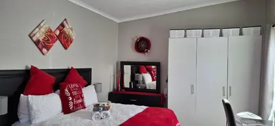 a bedroom with a bed with red pillows and a mirror at Christa's Place 897 in Pretoria
