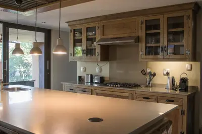 a kitchen with wooden cabinets and a large counter top at Duiker lodge in Mmukubyane