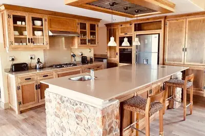 a kitchen with wooden cabinets and a large kitchen island at Duiker lodge in Mmukubyane