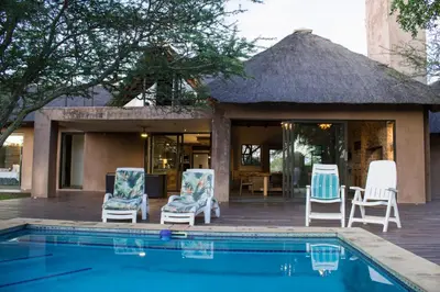 a group of chairs sitting next to a swimming pool at Duiker lodge in Mmukubyane