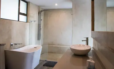 a bathroom with a tub and a sink and a shower at Duiker lodge in Mmukubyane