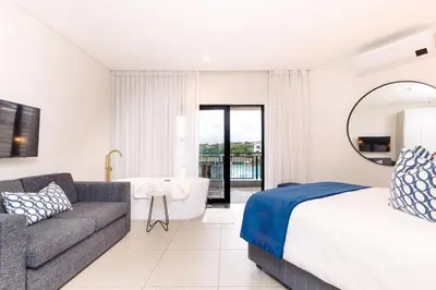 a bedroom with a bed and a couch and a tub at MINT Resorts The Blyde in Pretoria