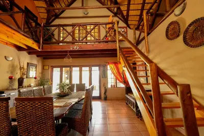 a dining room with a staircase and a dining table at Khaya Umdani Guest Houses in Marloth Park