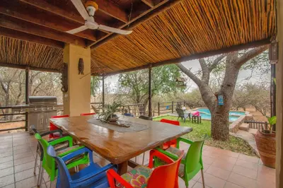 a dining room with a table and colorful chairs at Khaya Umdani Guest Houses in Marloth Park