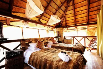a bedroom with two beds in a room with windows at Khaya Umdani Guest Houses in Marloth Park