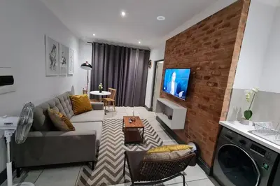 a living room with a couch and a tv at Upmarket one-bedroom apartment at Menlo Park in Pretoria