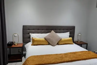 a bedroom with a large bed with gold pillows at Upmarket one-bedroom apartment at Menlo Park in Pretoria