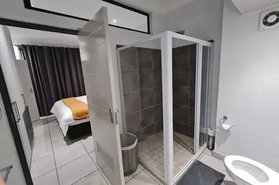 a bathroom with a shower with a toilet and a bed at Upmarket one-bedroom apartment at Menlo Park in Pretoria