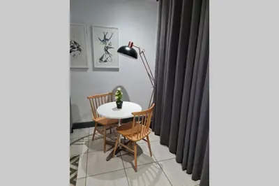 a dining room with a table and chairs and a lamp at Upmarket one-bedroom apartment at Menlo Park in Pretoria