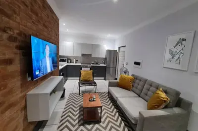 a living room with a couch and a flat screen tv at Upmarket one-bedroom apartment at Menlo Park in Pretoria