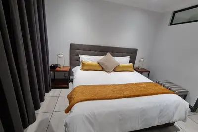a bedroom with a large bed with a brown blanket at Upmarket one-bedroom apartment at Menlo Park in Pretoria