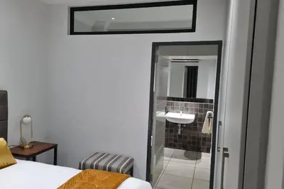 a bedroom with a bathroom with a shower and a sink at Upmarket one-bedroom apartment at Menlo Park in Pretoria