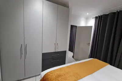 a bedroom with a bed and a large cabinet at Upmarket one-bedroom apartment at Menlo Park in Pretoria