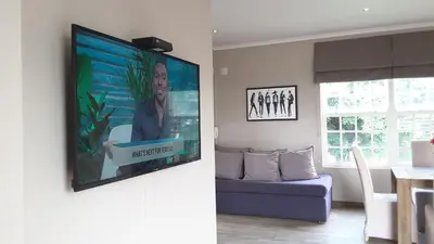 a flat screen tv hanging on a wall in a living room at Versailles in Pretoria