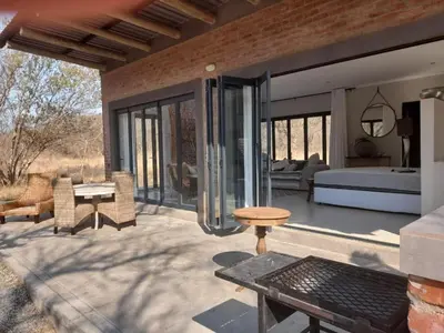 a patio with a bedroom and a bed and a table at Crocodile Sands River Lodge in Nelspruit