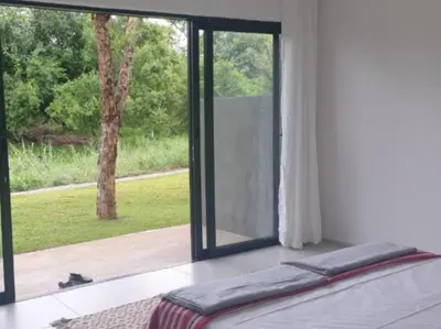a bedroom with a window with a cat looking out at Crocodile Sands River Lodge in Nelspruit