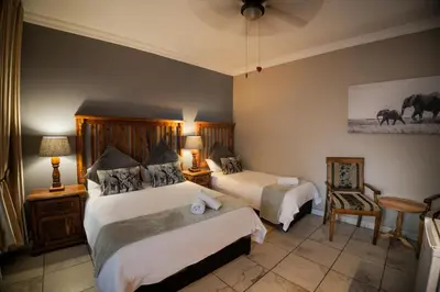 a hotel room with two beds and a chair at Ivory Tusk Lodge in Tzaneen