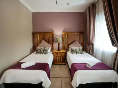a hotel room with two beds and a window at Ivory Tusk Lodge in Tzaneen
