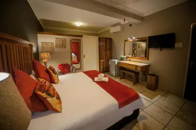 a bedroom with a large bed and a desk at Ivory Tusk Lodge in Tzaneen