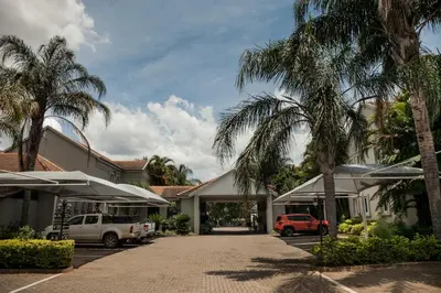 a car parked in front of a building with palm trees at Ivory Tusk Lodge in Tzaneen