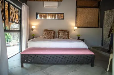 a bedroom with a large bed with a large window at hippomoon lodge game reserve in Hoedspruit