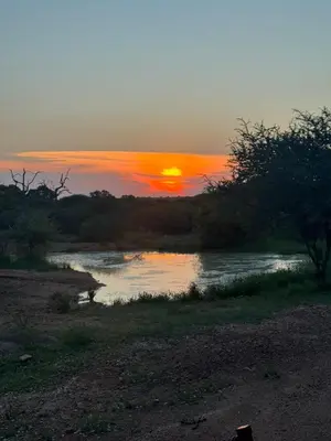 a sunset over a river with the sun setting at Kwalata Game Lodge in Klipdrift