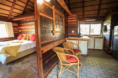 a bedroom with a bed and a kitchen in a cabin at Kwalata Game Lodge in Klipdrift