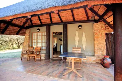 a patio of a house with a table and chairs at Kwalata Game Lodge in Klipdrift