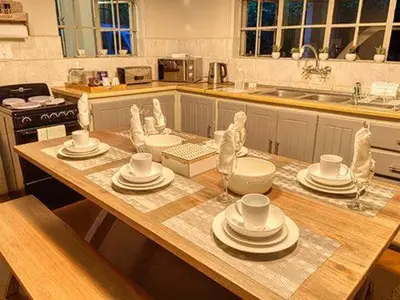 a kitchen with a wooden table with plates and bowls at Kruger park House in Hazyview