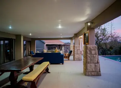 a living room with a table and a pool at Elements Private Golf Villa 295 in Mabula