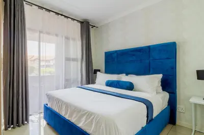 a blue bed in a room with a large window at Buckingham Palace 2 Bed 2 Bath in Midrand