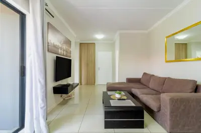 a living room with a couch and a tv at Buckingham Palace 2 Bed 2 Bath in Midrand
