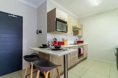 a kitchen with a counter and two stools in it at Buckingham Palace 2 Bed 2 Bath in Midrand