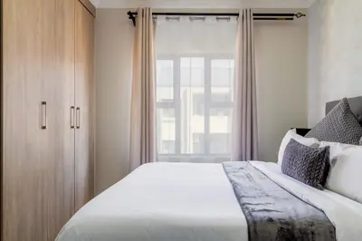 a bedroom with a large bed and a window at Buckingham Palace 2 Bed 2 Bath in Midrand