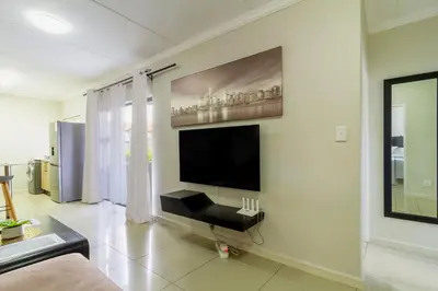 a living room with a flat screen tv on a wall at Buckingham Palace 2 Bed 2 Bath in Midrand